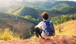 A-person-with-a-backpack-overlooks-green-mountains.