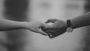 Close-up of two people gently holding hands, symbolizing trust, connection, and emotional support through therapy.