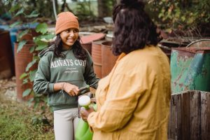 Teen girl smiling and talking with an adult while gardening, representing positive connections and emotional growth