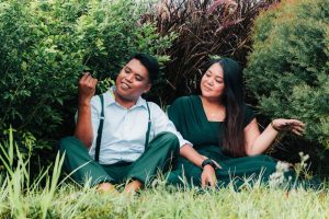 A romantic couple sitting amidst lush greenery, enjoying each other's company and nature.